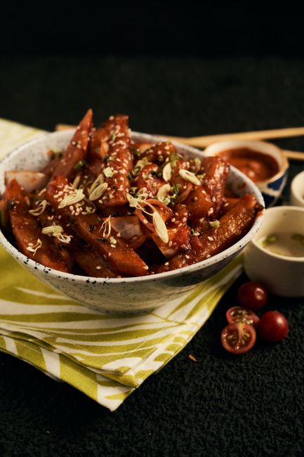 Delicious spicy tteokbokki served in a bowl with garnishes and side dishes.