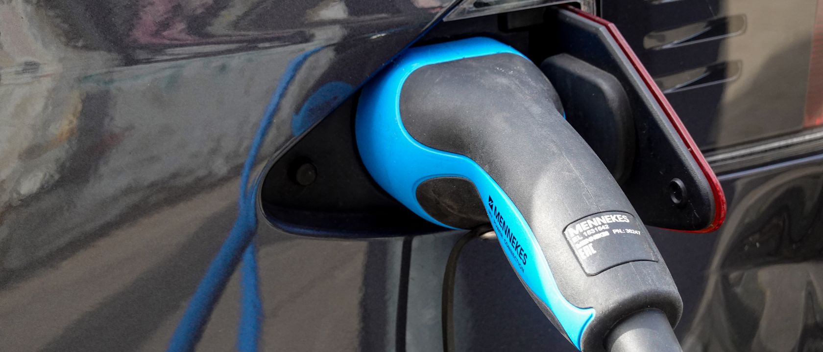 Close-up of an electric vehicle being charged using a Mennekes EV connector.
