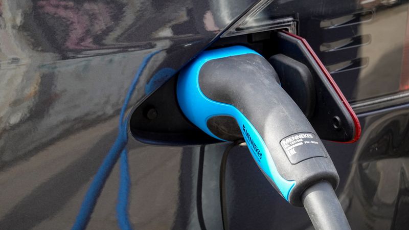 portable EV charger plugged into an outdoor wall outlet during a heavy rainstorm