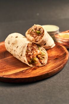 A close-up of a savory burrito filled with beans, vegetables, and meat on a wooden plate, perfect for lunch.