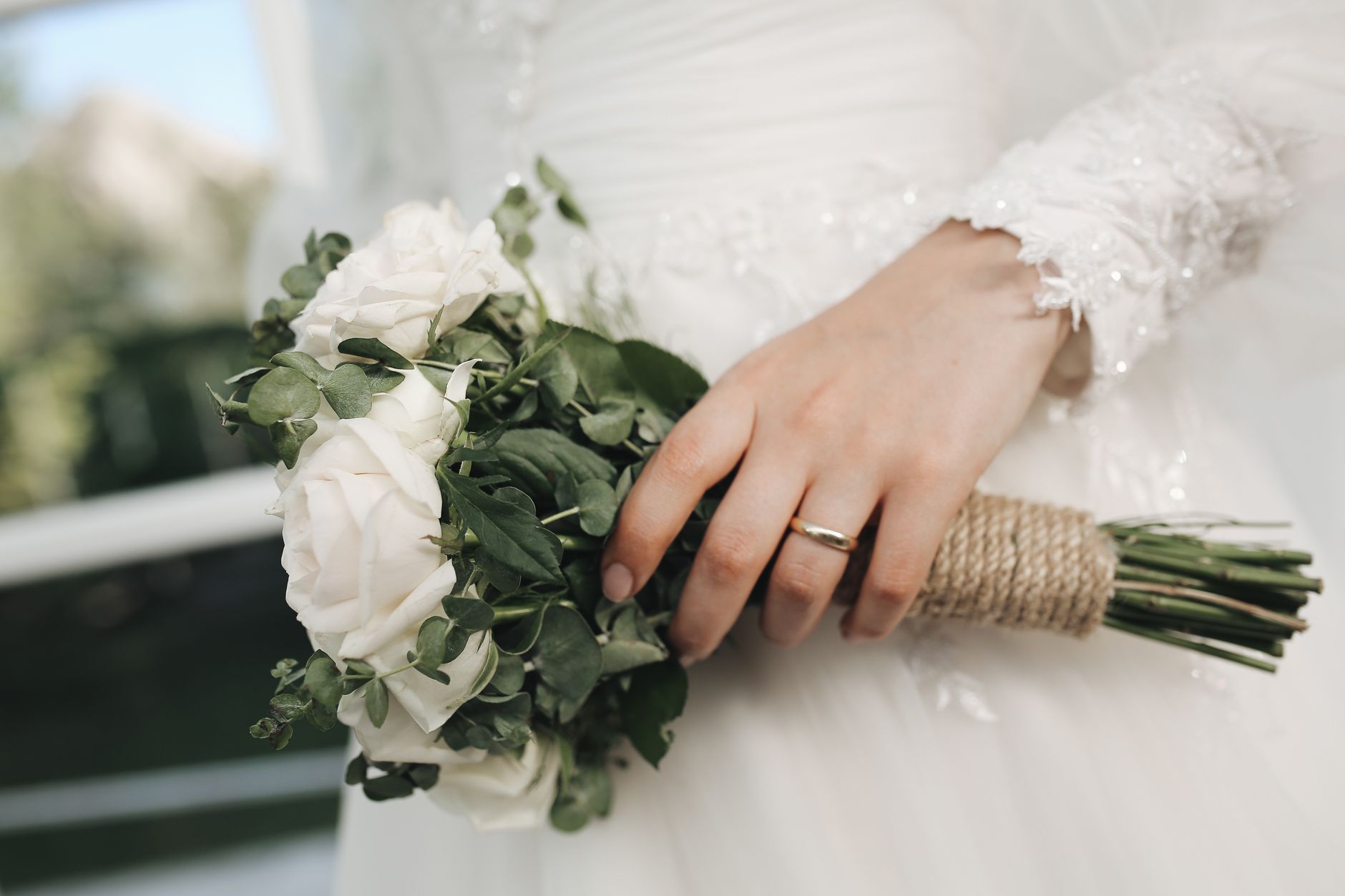 Close-up of a bridal bouquet with white roses and greenery in an elegant wedding setting.