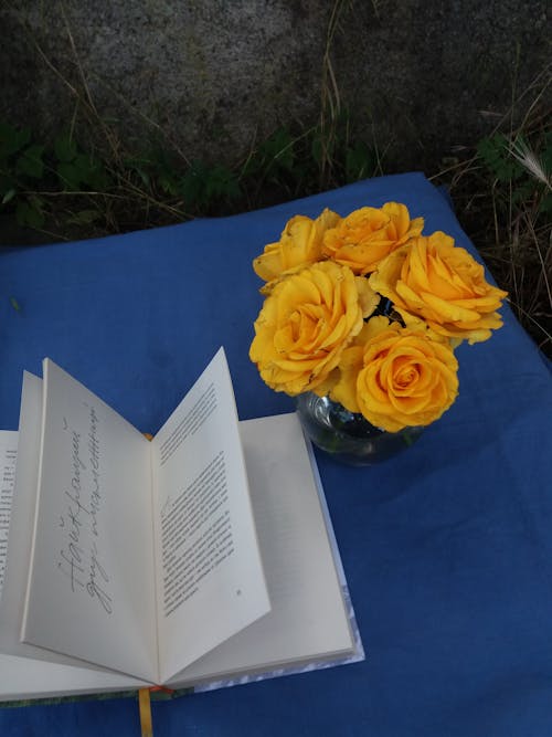 An Open Book and Yellow Flowers on the Table