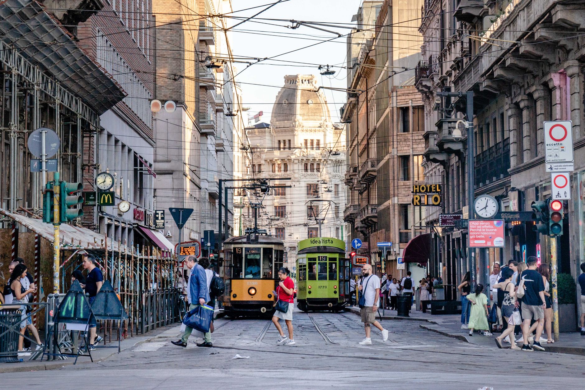 A lively street in Milan featuring historic trams, busy pedestrians, and elegant architecture.