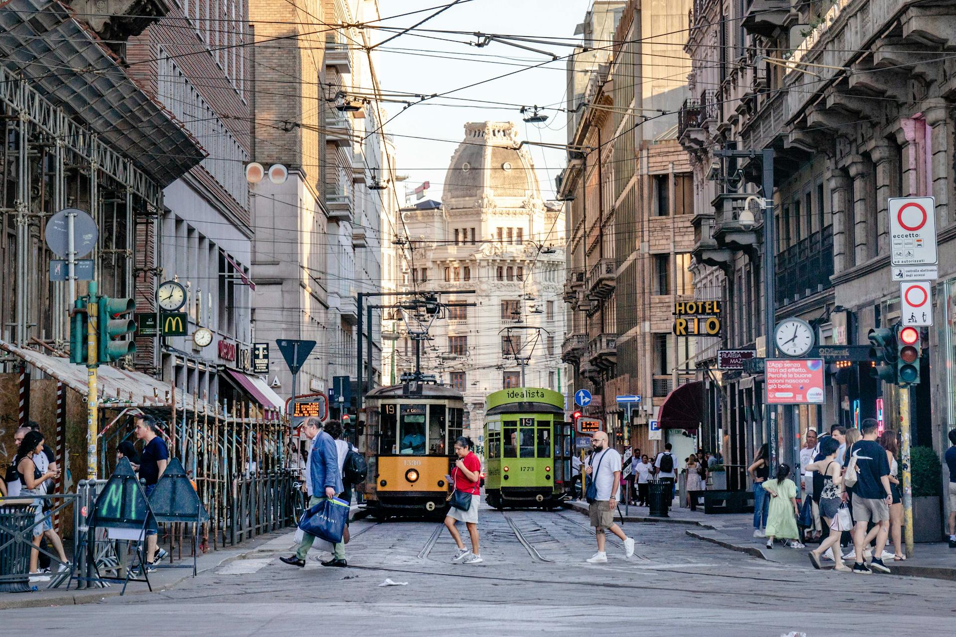 A lively street in Milan featuring historic trams, busy pedestrians, and elegant architecture.