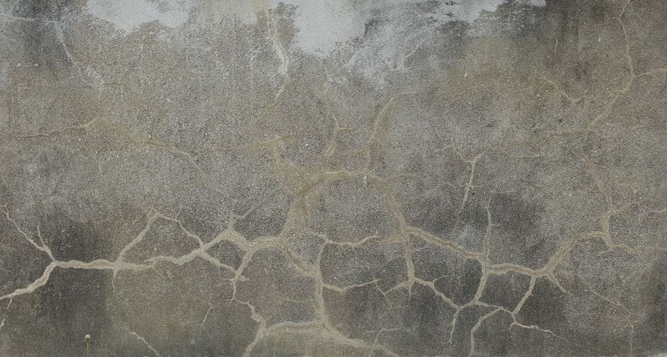Close-up of a weathered concrete wall with detailed cracks and textures, ideal for backgrounds and design projects.