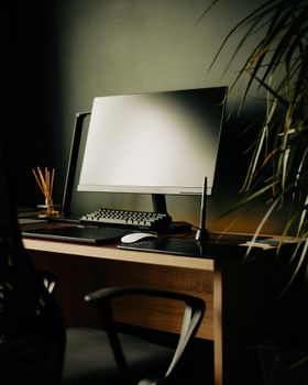 A sleek home office setup featuring a computer, keyboard, and chair, with warm lighting.