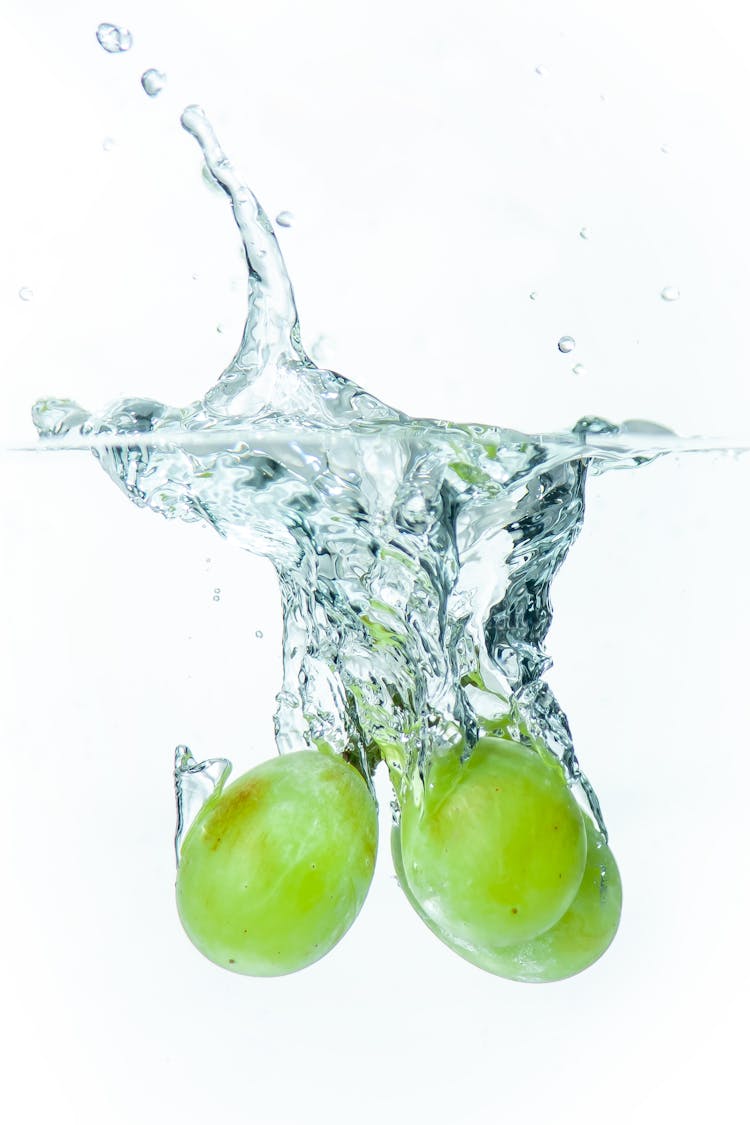 Close-up Of Green Grapes Falling Into Clear Water 