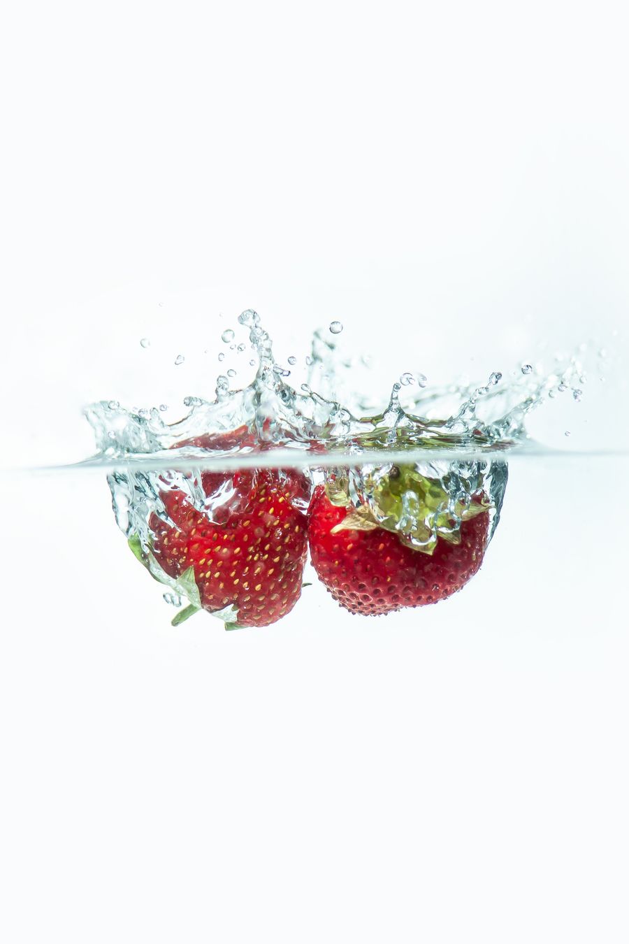 Vibrant strawberries captured mid-splash against a white background
