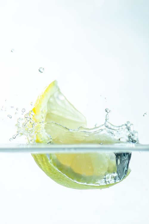 Free A lemon slice splashes into clear water, creating a fresh and vibrant scene. Stock Photo