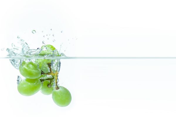 Fresh green grapes creating a splash as they dive into clear water
