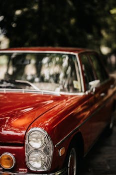 Close-up of a classic red vintage car with nostalgic charm in an outdoor setting.