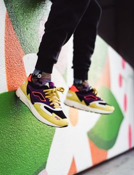 Trendy sneakers and jogging pants in front of a vivid graffiti backdrop.
