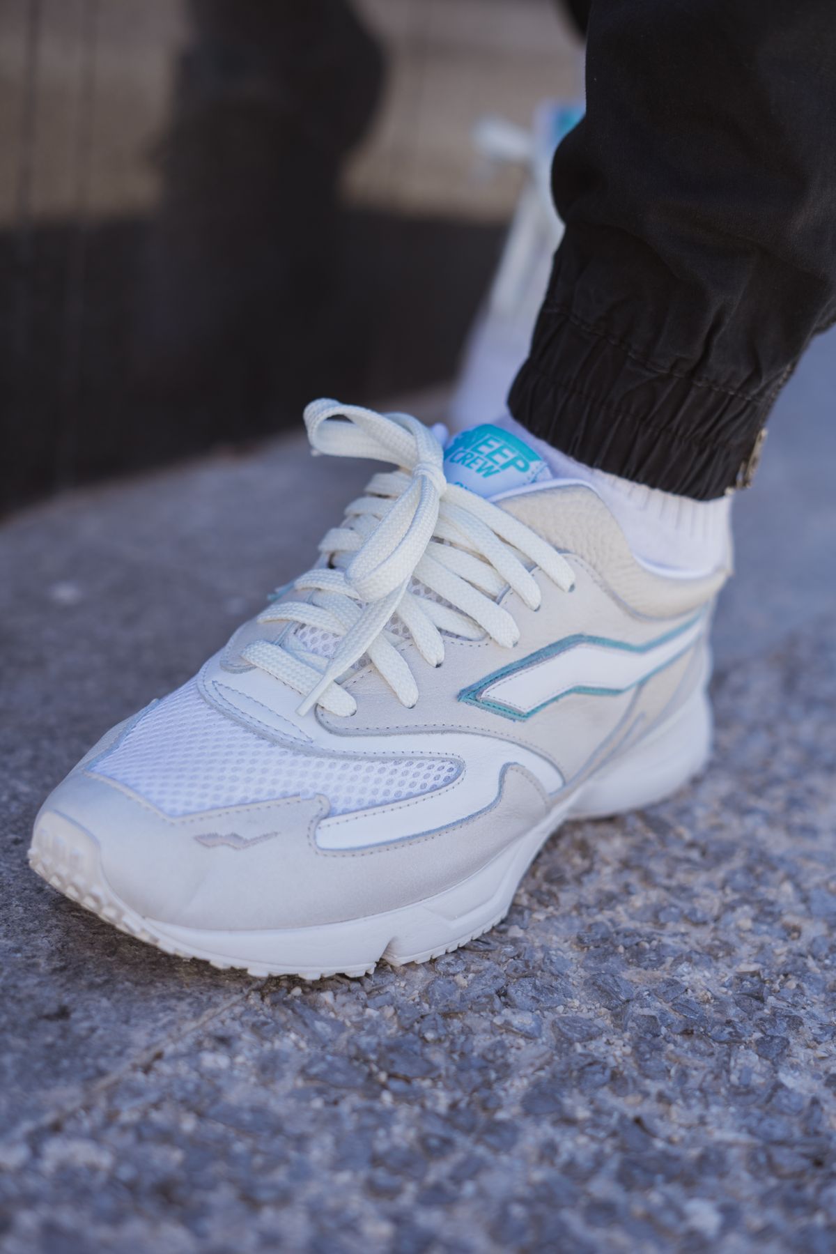 Scarpa da corsa in pelle bianca e mesh su cemento grigio