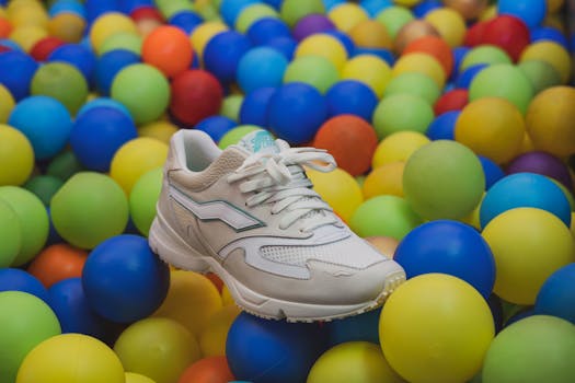 A stylish white sneaker surrounded by vibrant, colorful play balls.