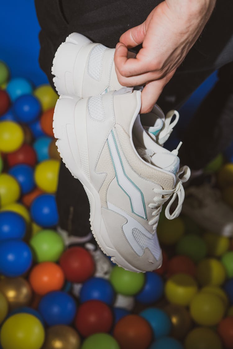 Man Holding A Pair Of White Sneakers 