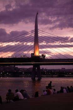 Dramatic sunset over Halic Metro Bridge in Istanbul with people by the waterfront.