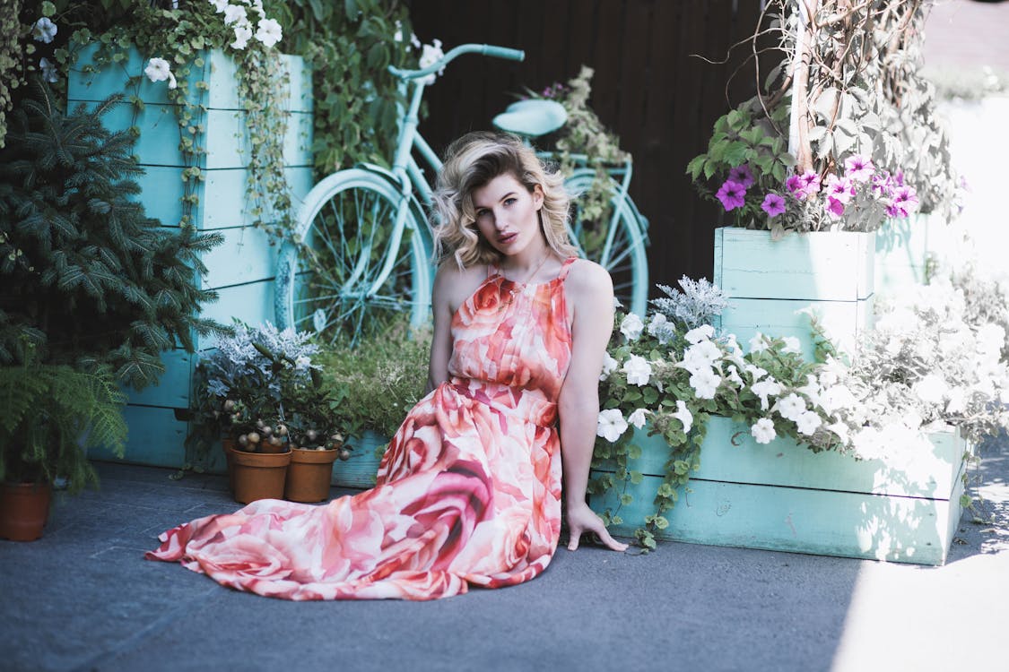 Free Woman Seated on the Floor Surrounded By Flowering Plants Stock Photo