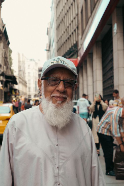 Free Elderly man with beard and eyeglasses smiling on a bustling city street. Stock Photo