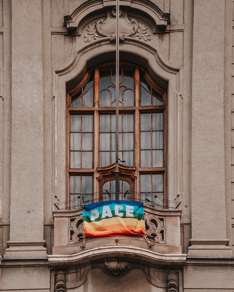 Photo Of A Building Facade With A Balcony And Flag Where Is Written 