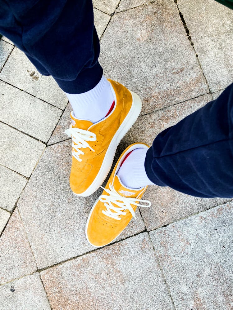 Photo Of A Legs Wearing Yellow Sneakers, White Sock And Blue Navy Trousers