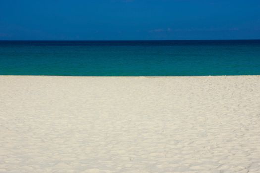 A tranquil beach with white sand and blue ocean under a clear sky in Kalaoa, Hawaii.