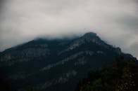 山峰上雾气弥漫，天空多云，营造出神秘的氛围