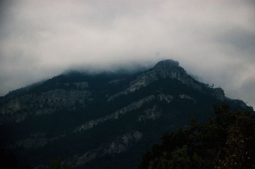 山峰上雾气弥漫，天空多云，营造出神秘的氛围