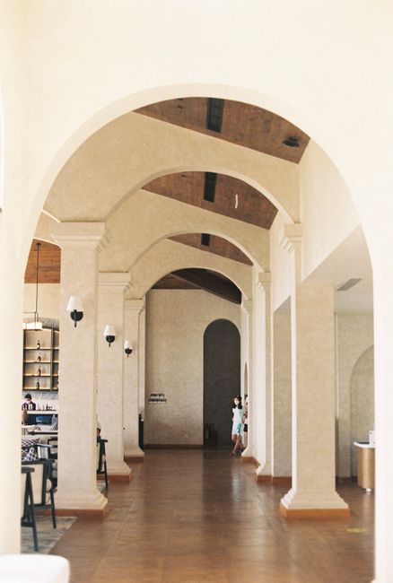 A sophisticated hallway showcasing elegant arches and columns in a bright interior setting.