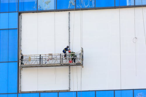 Men Working on Scaffolding near Advertisement Board on Building