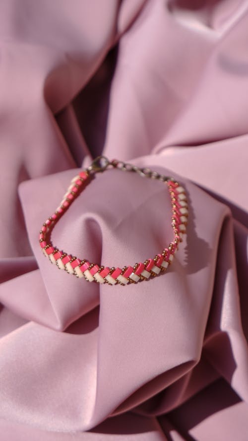 Close-Up Shot of a Beaded Bracelet on Pink Textile