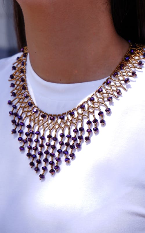 A Person in White Shirt Wearing Purple Beaded Necklace