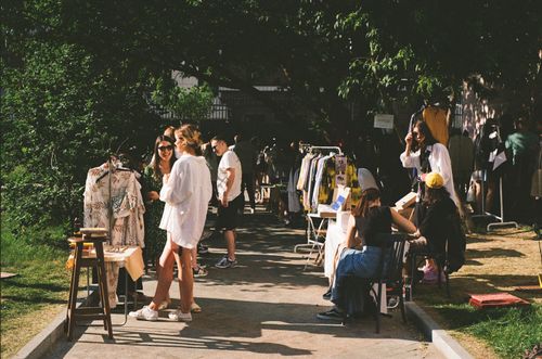 Free Vibrant street market scene with people shopping for clothes on a sunny day. Stock Photo