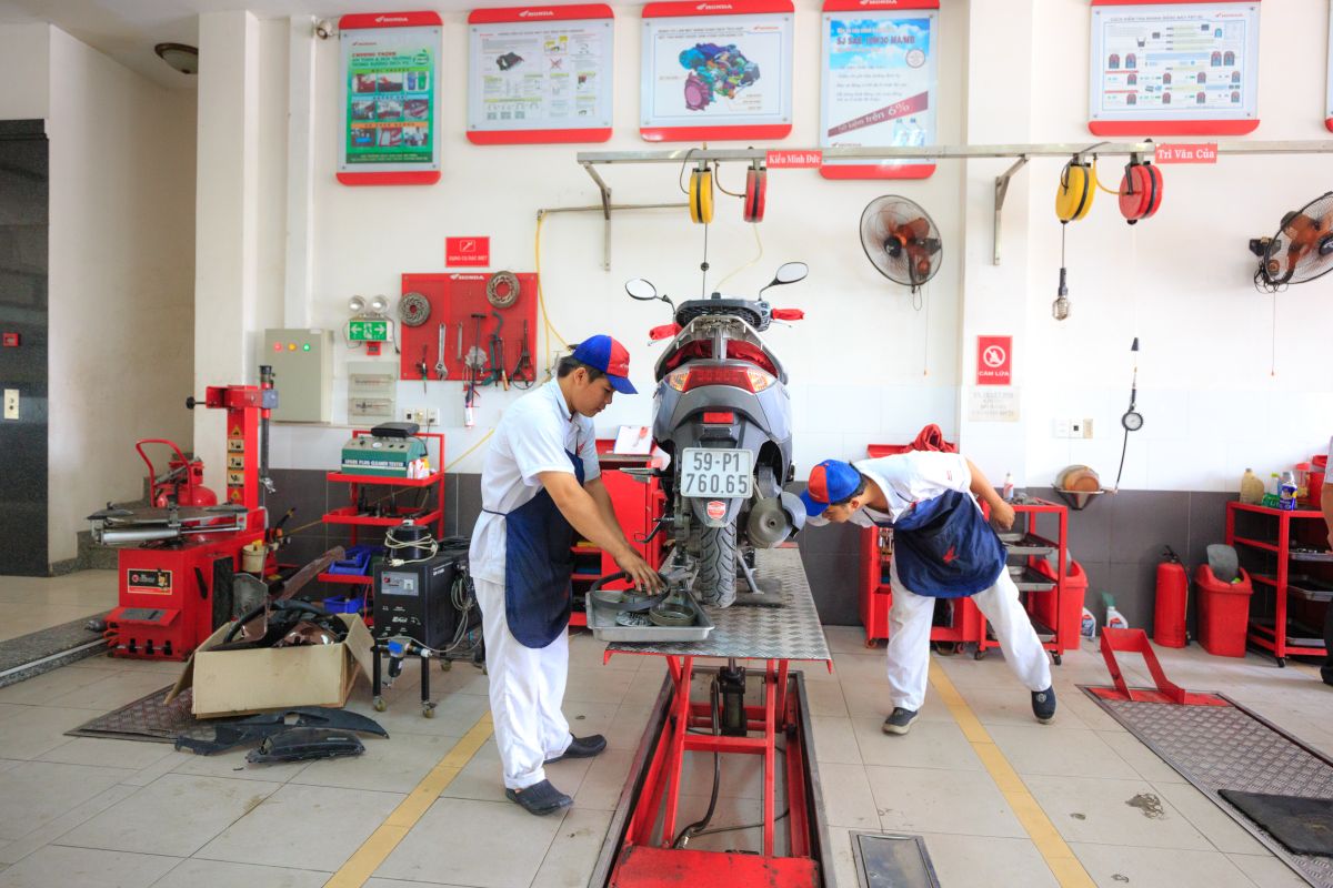 Technicians servicing a motorcycle together in a well-equipped repair bay