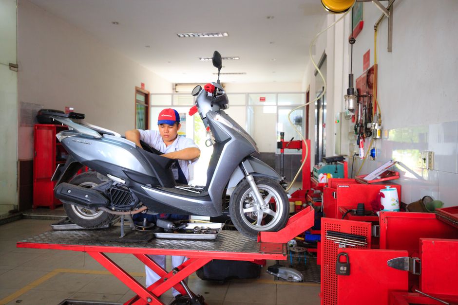 Meccanico che esegue la manutenzione di uno scooter in officina