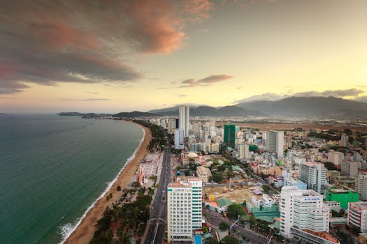 A stunning aerial view of a coastal city at dawn with a vibrant skyline and scenic coastline.