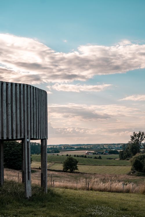 Free A picturesque rural landscape with fields, a cloudy sky, and wooden structure. Stock Photo