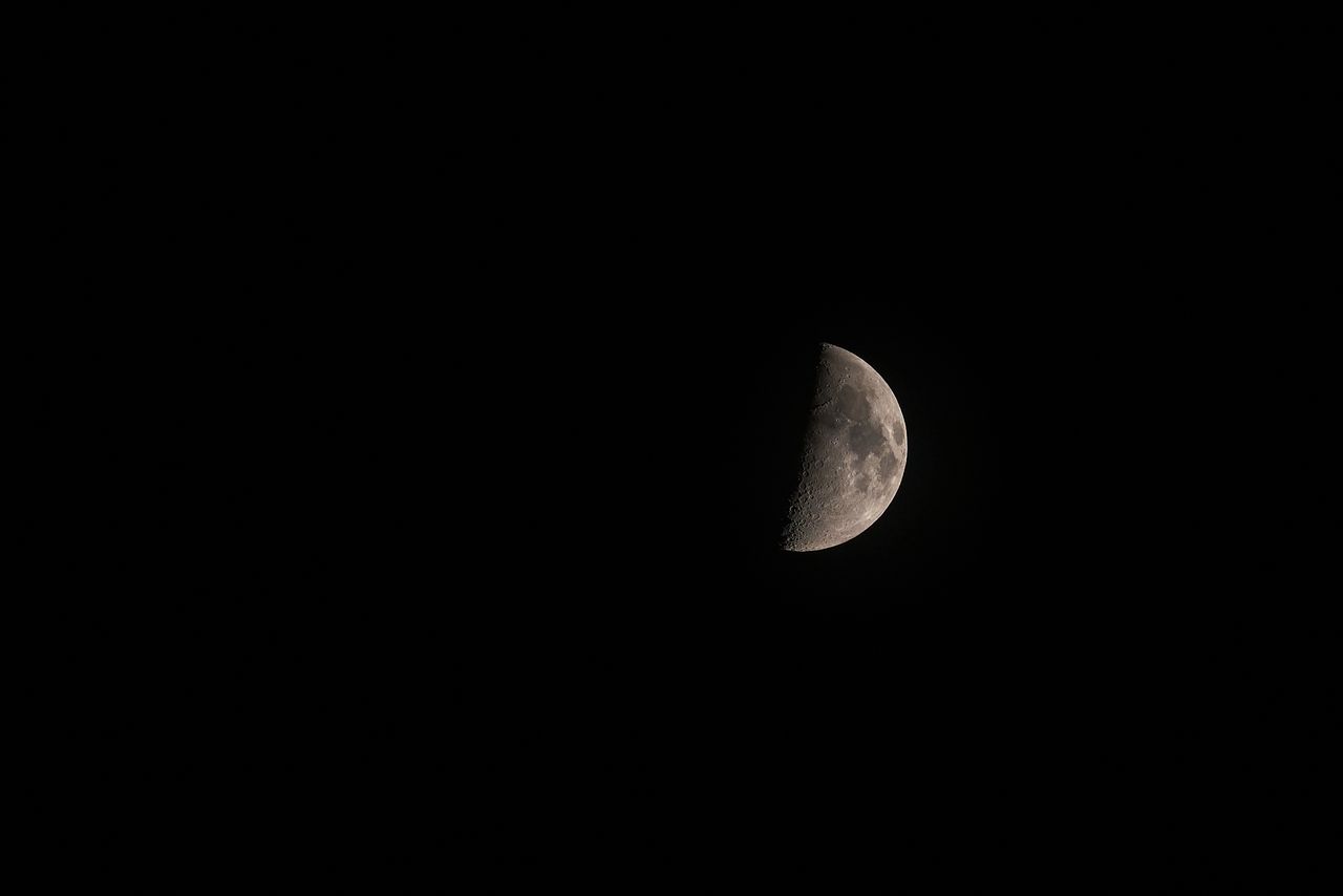 a detailed photograph of the half moon in a dark night sky showcasing