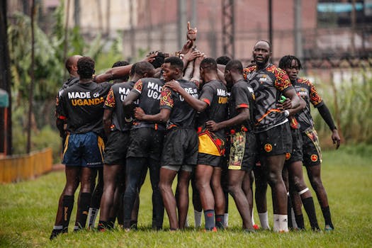 Ugandan rugby team in a huddle, showcasing unity and sportsmanship on a grassy field.