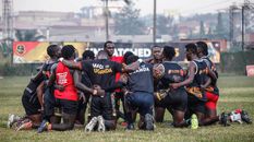 Rugby players kneeling together forming a huddle on a field, highlighting teamwork and unity.