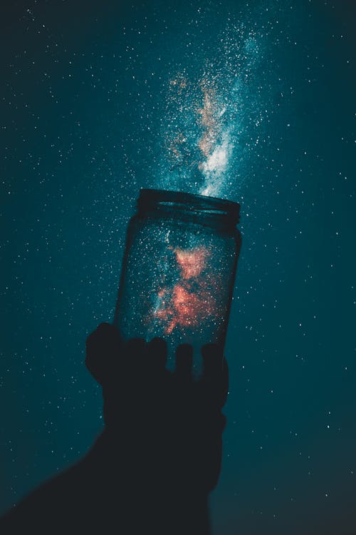 Free Creative Photo of Person Holding Glass Mason Jar Under A Starry Sky Stock Photo