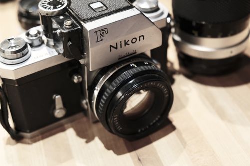 Free Close-up of a retro vintage Nikon camera resting on a wooden surface. Stock Photo