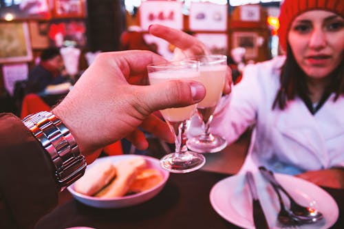 Mann, Der Silberne Link Uhr Trägt, Die Ein Glas Hält, Das Weiße Flüssigkeit Vor Einer Frau Enthält