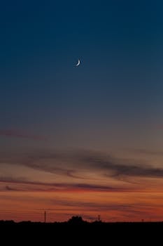 A peaceful crescent moon with a vibrant sunset background creating a stunning nightscape.