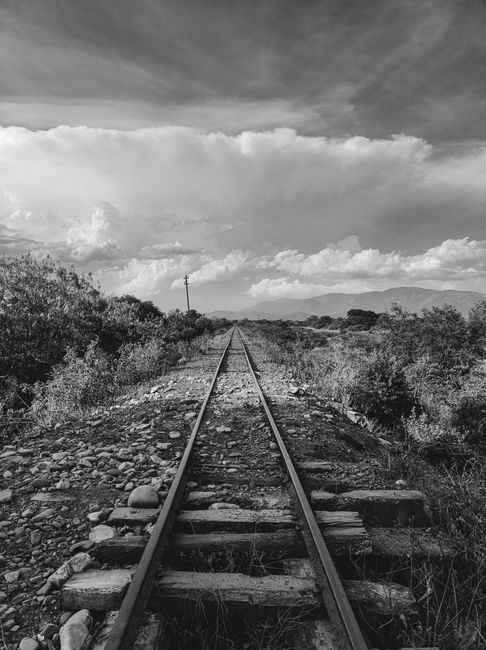 Black and white view of a railway track with a dramatic sky in San Salvador de Jujuy.
