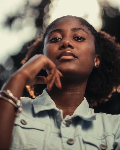 Free Low angle portrait of a young woman with a bokeh background, highlighting her poise and confidence. Stock Photo