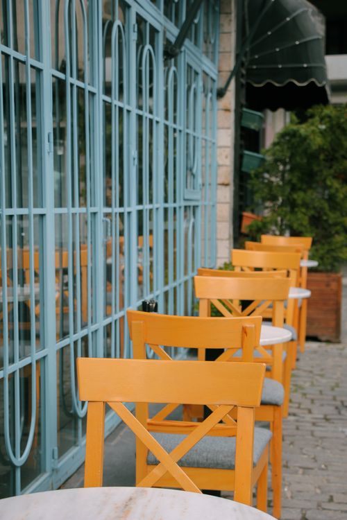 Free A row of yellow chairs at a sidewalk café, creating a vibrant and inviting atmosphere. Stock Photo