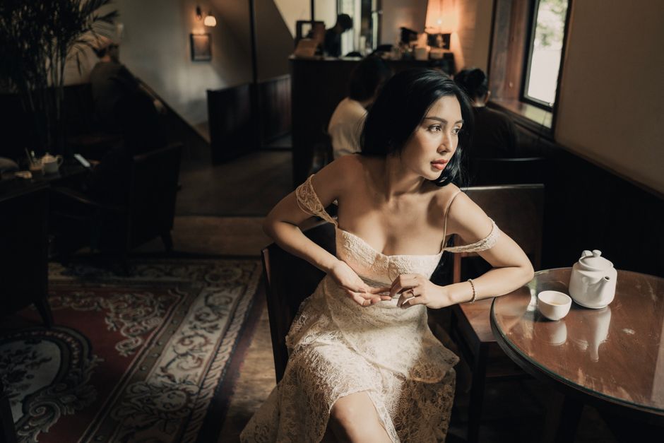A woman in an elegant dress sitting at a table in a cozy café, enjoying the ambiance.