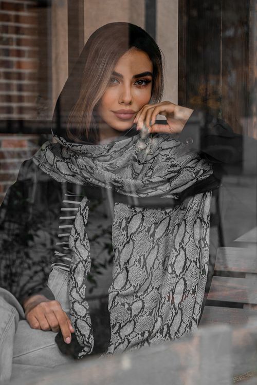 Free Stylish woman with patterned scarf posing behind a glass window indoors. Stock Photo