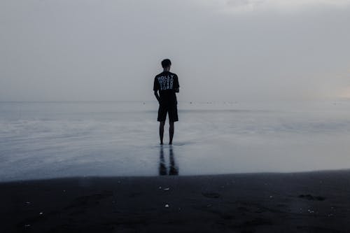 Man Standing in Water on Shore