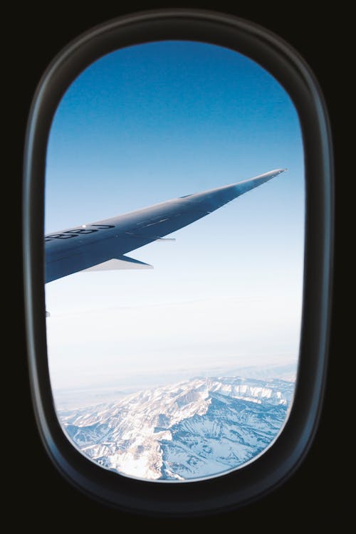 Правое крыло серых самолетов с видом на заснеженные горы, вид из окна